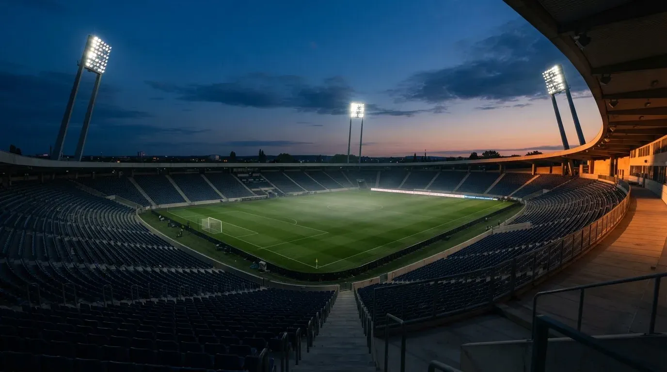 An empty football stadium with floodlight masts at dusk