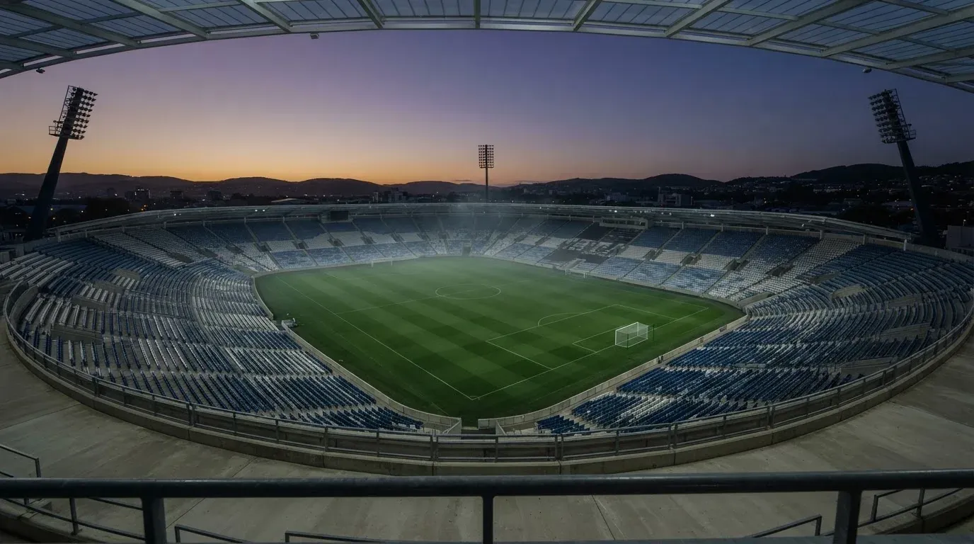 An empty football stadium with floodlight masts at dusk
