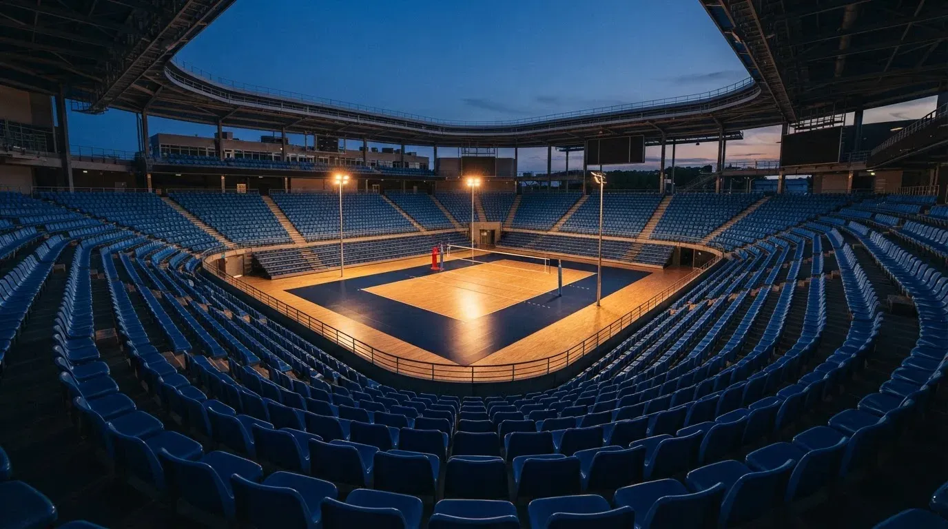 An empty football stadium with floodlight masts at dusk
